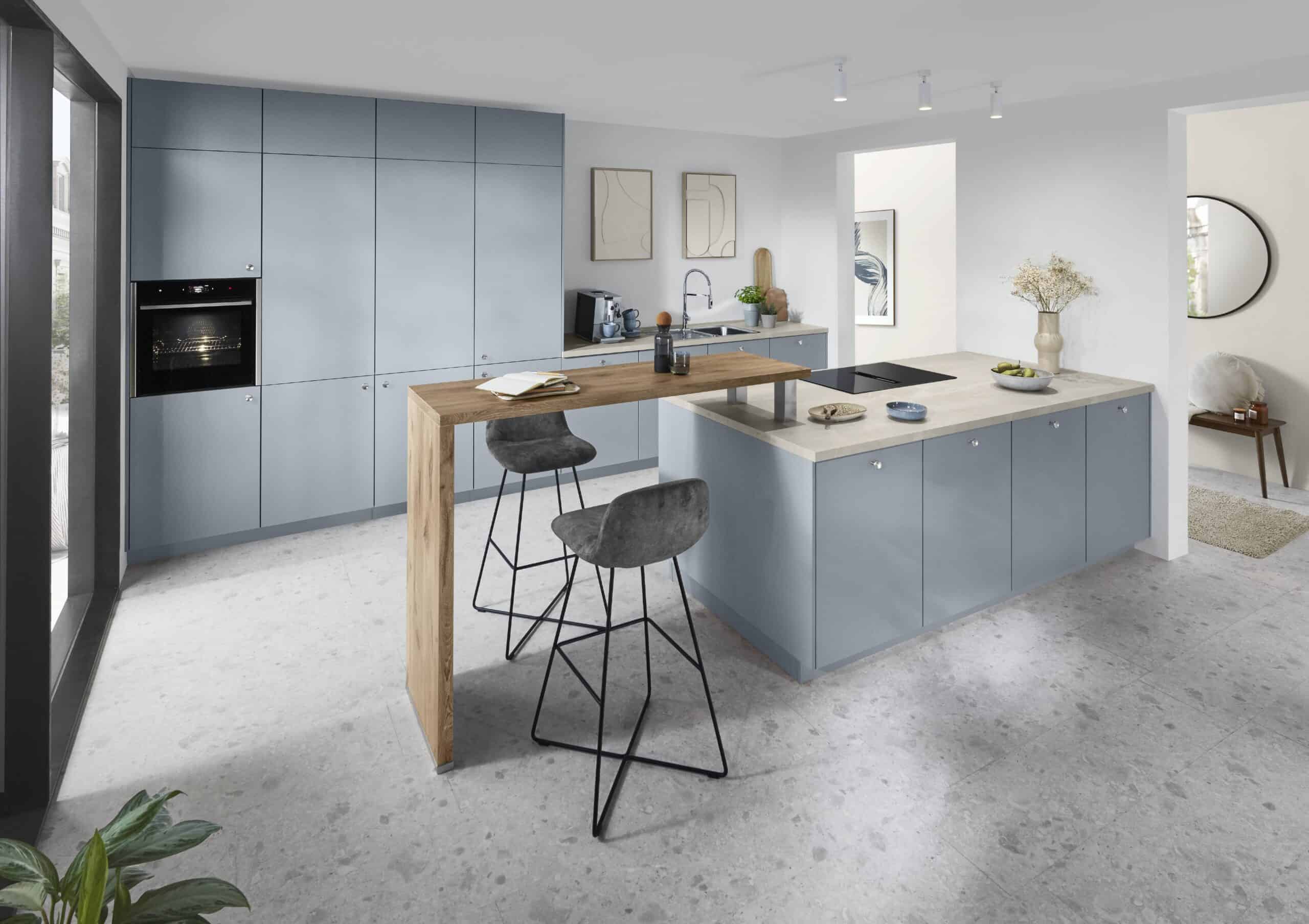 Moderne blaue Küche mit Holz-Esstheke und Barhockern, helle Raumgestaltung.