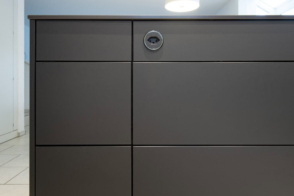 Dunkle Küchenschränke mit integrierter Steckdose, modernes Design.