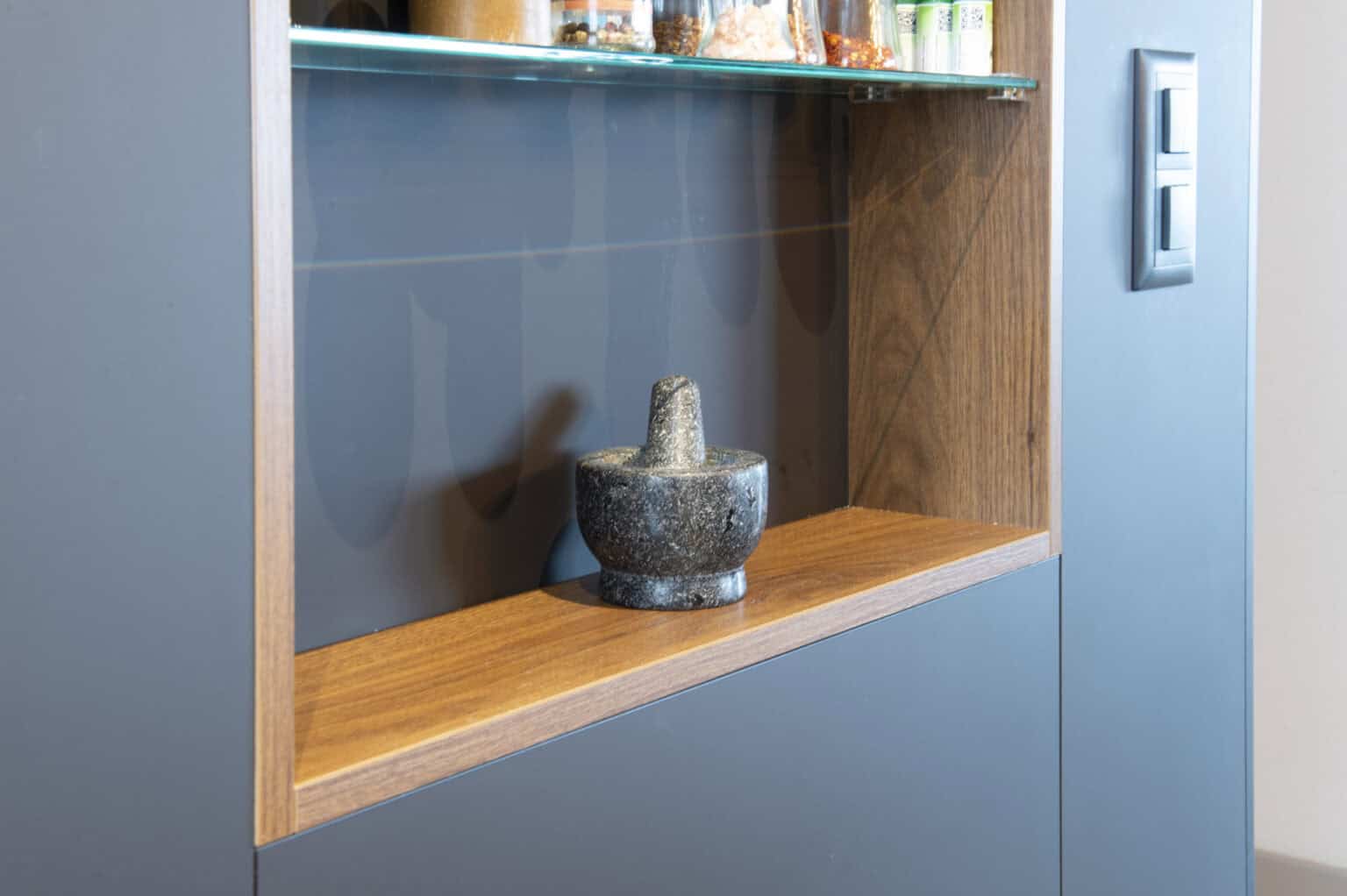 Moderne Küchenzeile mit stilvollem Holzregal und blauer Wandgestaltung.