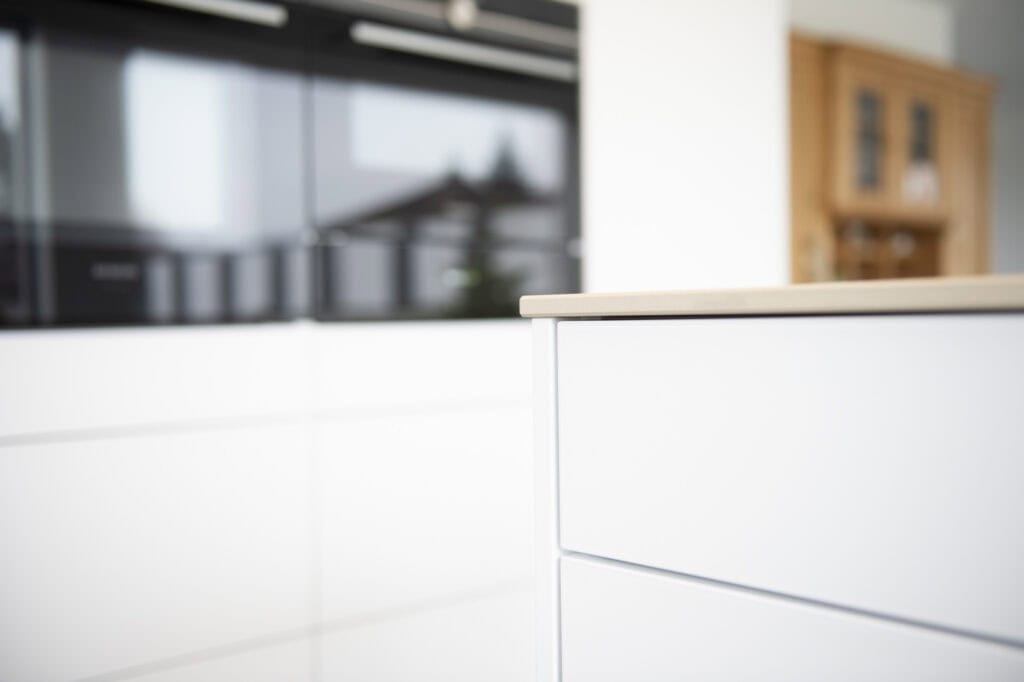 Moderne weiße Küchenmöbel mit klaren Linien und minimalistischer Gestaltung.