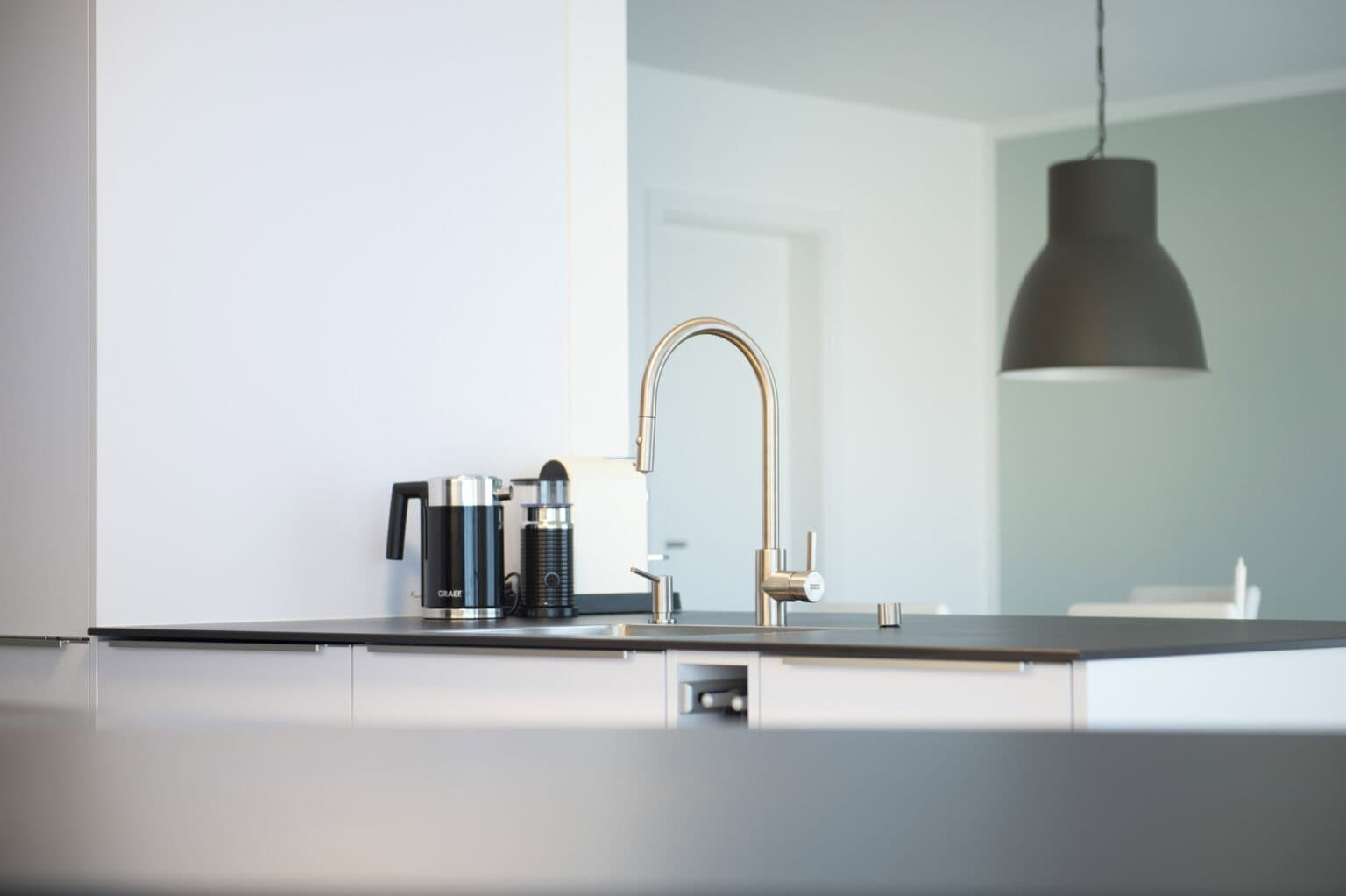 Helle Küche mit Wasserhahn und Hängelampe