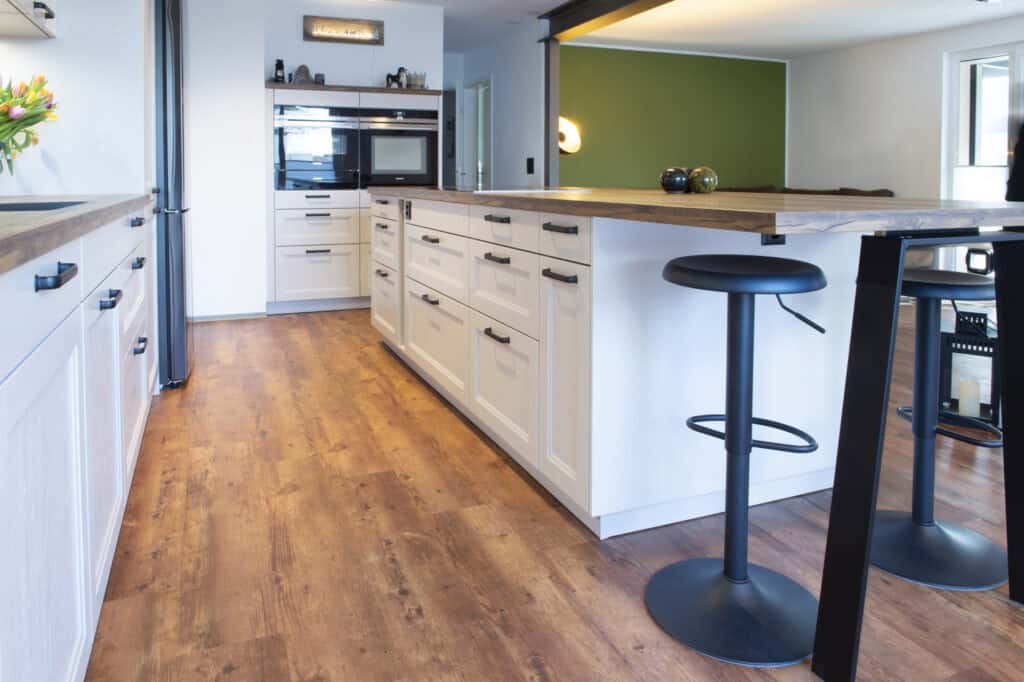 Große weiße Küche mit Sitzbereich und Holzfußboden