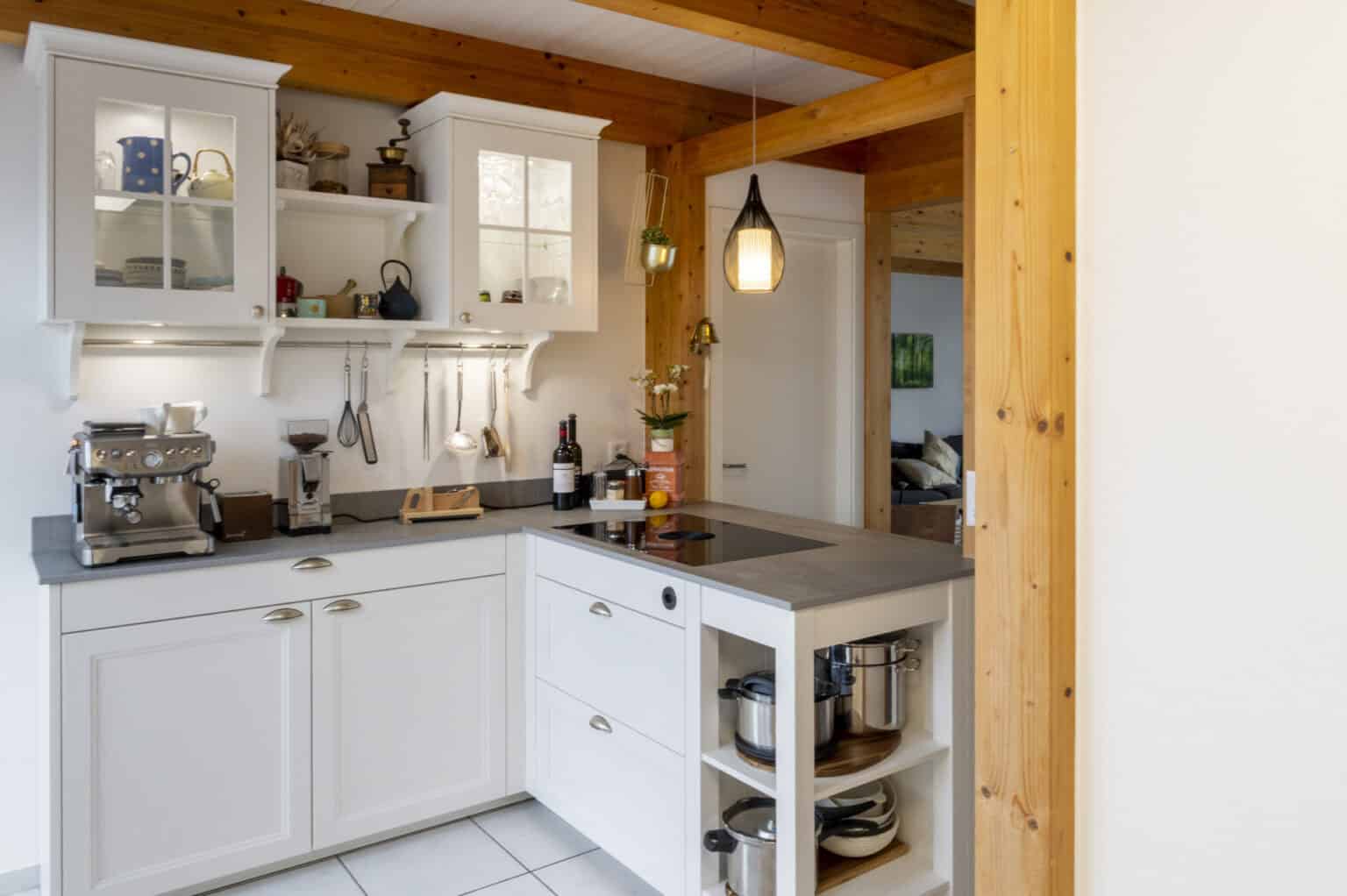 Weisse Landhausküche mit Holzbalken und Arbeitsplatte aus Dekton-Keramik in Betonoptik