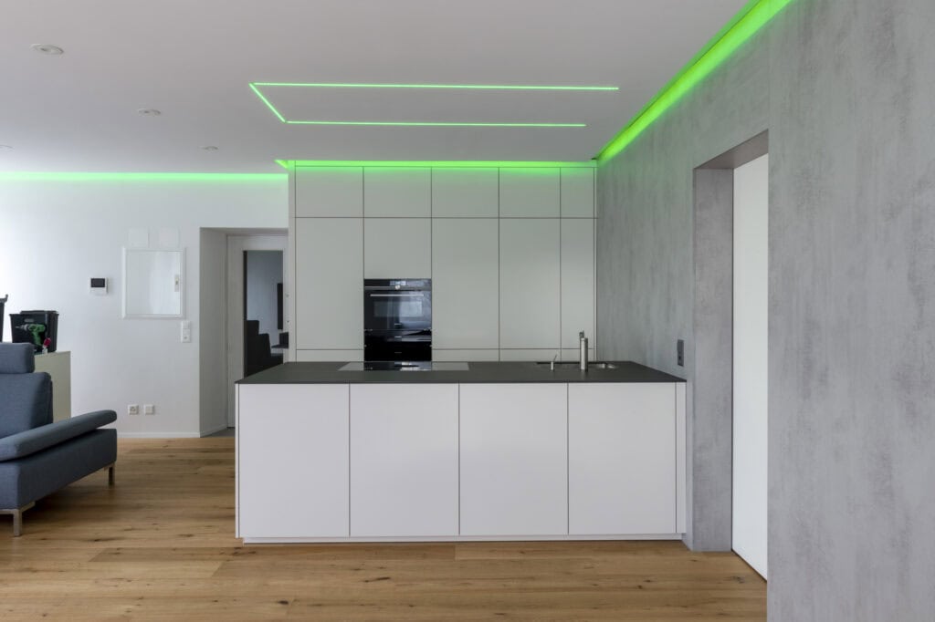 Küche mit grüner LED-Deckenbeleuchtung und weißem Küchenschrank
