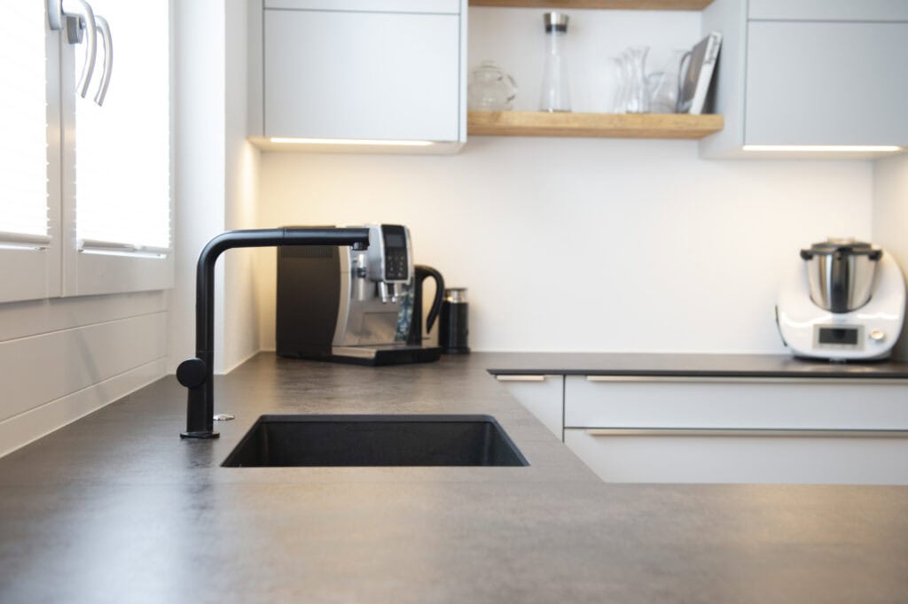 Moderne Küche mit schwarzer Spüle, Küchenmaschine und Wasserhahn, stilvolle Einrichtung für zeitgemä.