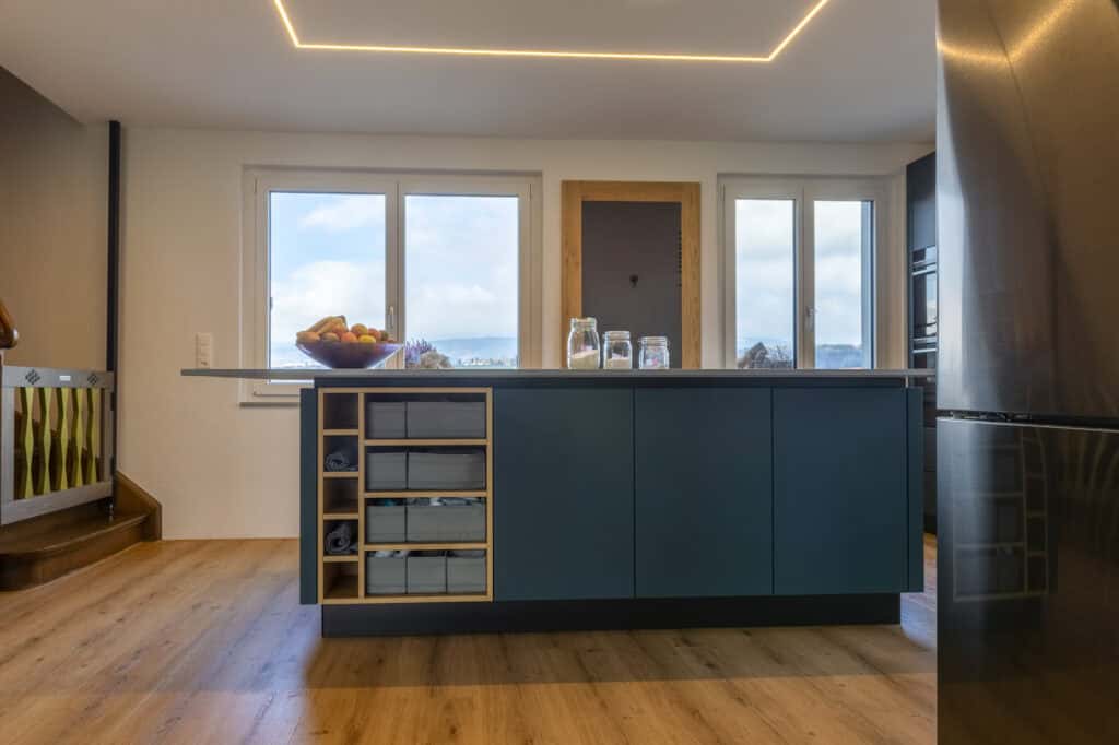 Moderne Kücheninsel mit Meerblick, helle Fenster, stilvolle Kücheneinrichtung.