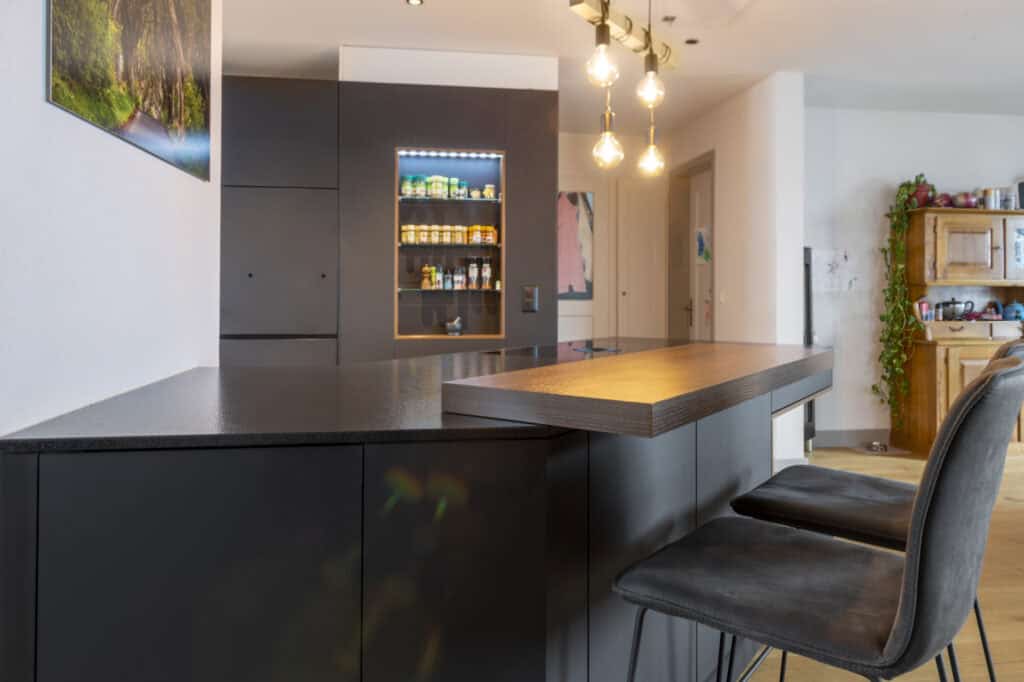 Moderne Kücheninsel mit dunklem Design, Holzarbeitsfläche und stilvollen Barhockern. Perfekt für mod.