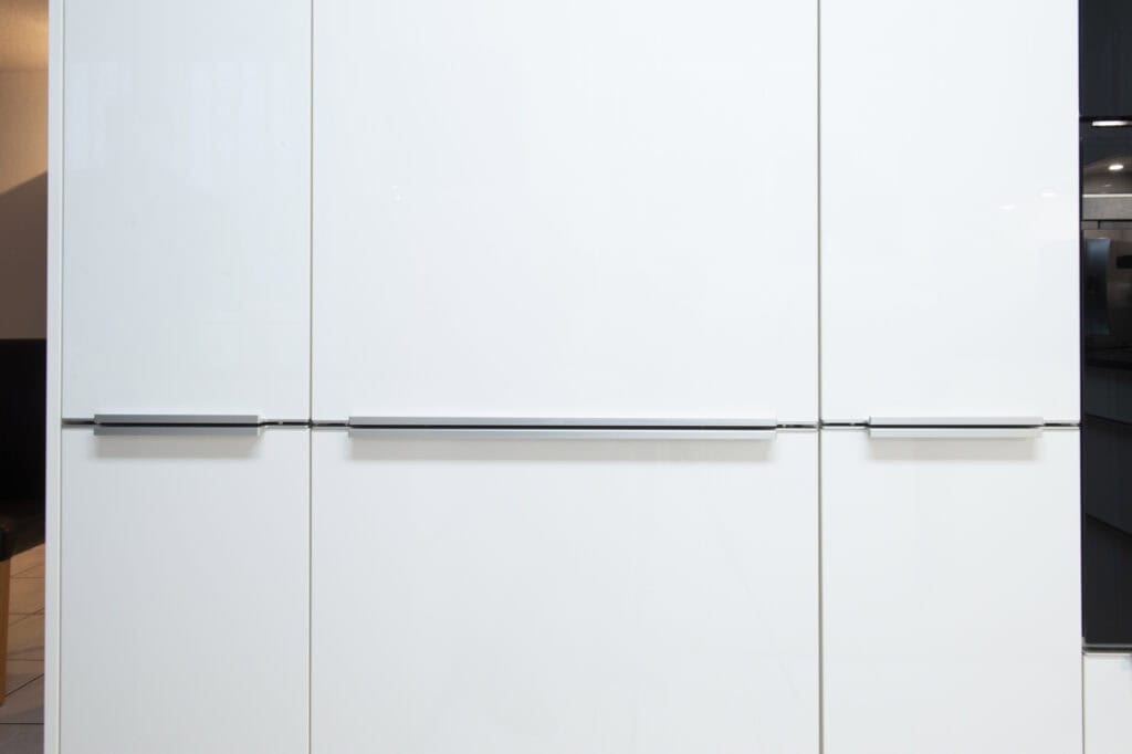 Weiße Küchenmöbel mit glatten Oberflächen und eleganten Griffen, ideal für moderne Küchen.