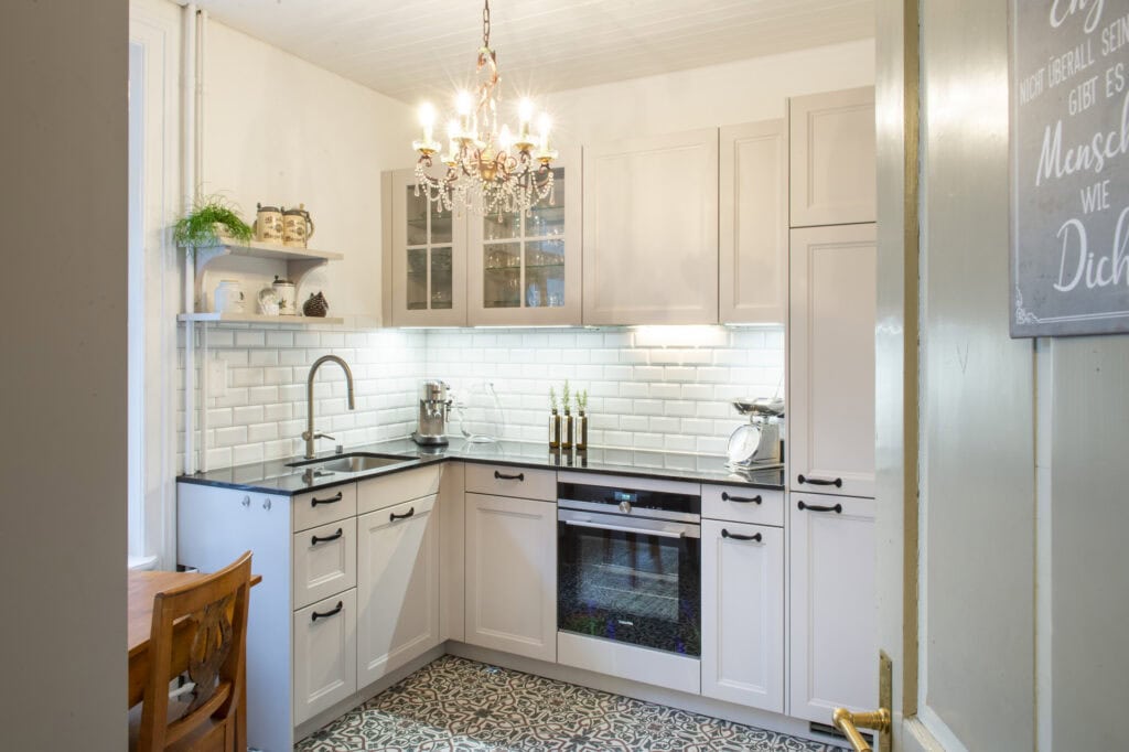Weiße Küche mit moderner Ausstattung, Backofen und eleganten Mosaikfliesen für stilvolles Kochen.