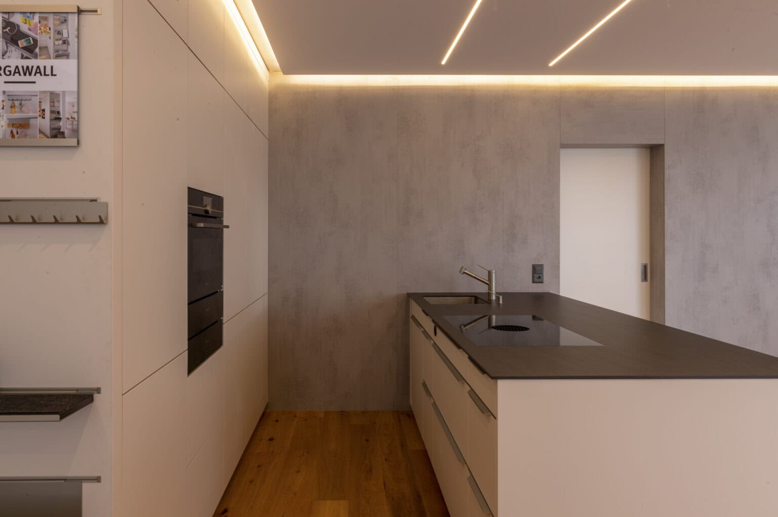 Helle Küche mit LED-Lichtstreifen vor einer betonartig wirkenden Wandfläche