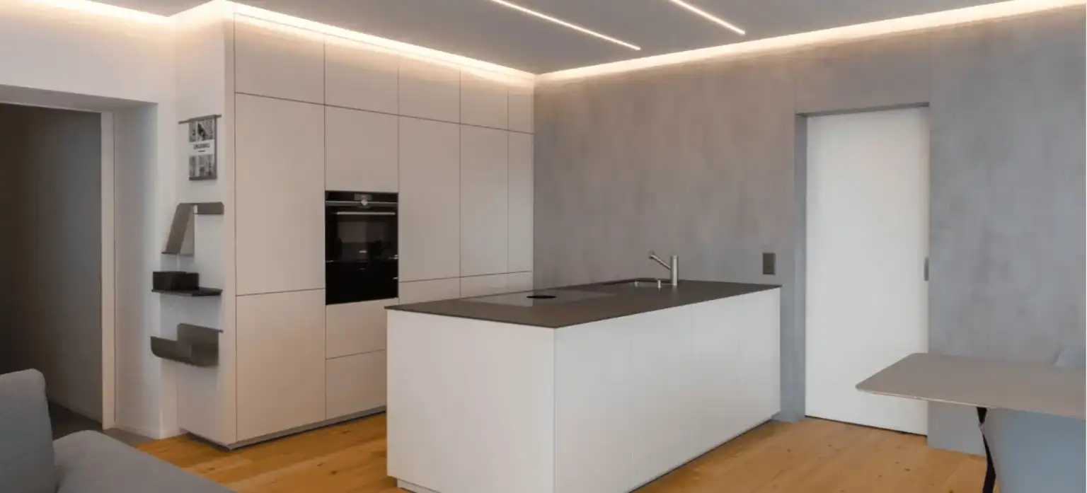 Minimalistische Designküche mit Kochinsel, grifflosen Fronten und Betonwand in moderner Wohnumgebung